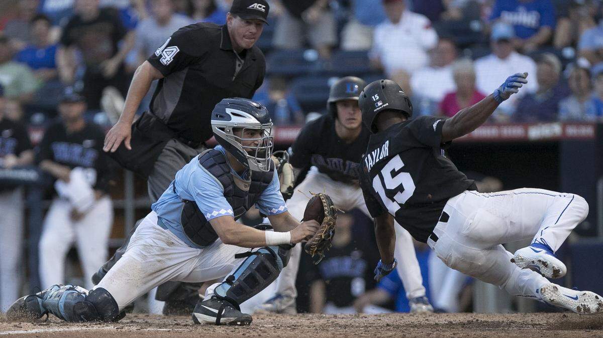 Duke's Kennie Taylor (15) scores on a single by Jimmy Herron in the bottom of the fifth inning to give Duke a 3-0 lead over North Carolina on Friday, May 11, 2018, at the Durham Bulls Athletic Park in Durham, N.C. North Carolina catcher Brandon Martorano (4) missed the tag, the play was reviewed and Taylor was called safe.