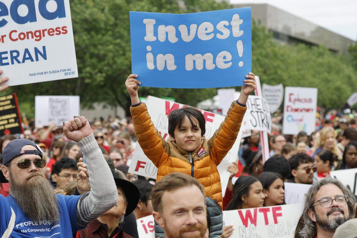 Maddox Cobb, 7, of Raleigh listens to the speakers during a rally to protest for more school funding at Halifax Mall in downtown Raleigh, N.C., Friday, May 1, 2026. The North Carolina Association of Educators has mobilized teachers from across the state to march on the Legislative Building to demand higher pay, more school funding and higher taxes on corporations. 