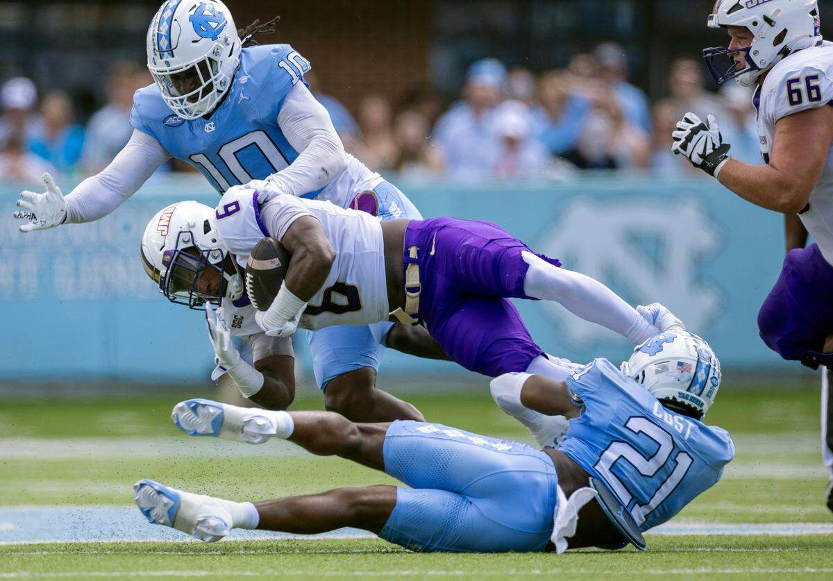 North Carolina defensive lineman Desmond Evans (10) and (21) defensive back Kaleb Cost (21) work to stop James Madison running back George Pettaway (6) after a two yard gain in the first quarter on Saturday, September 21, 2024 at Kenan Stadium in Chapel Hill, N.C. Pettaway, a former Tar Heel rushed for 65 yards in the first half.