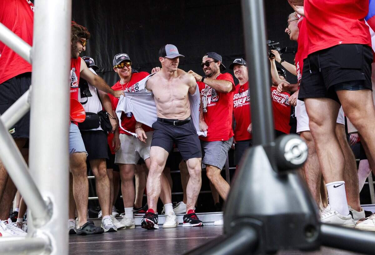 Rod Brind'Amour, head coach of the Carolina Hurricanes, has his shirt ripped off by his players as he prepares to lift the Stanley Cup during a rally on Saturday, June 20, 2026, in downtown Raleigh.