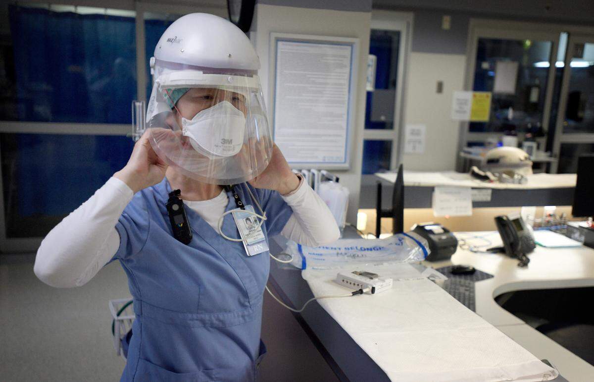 Registered nurse Qingxiao Cheng adjusts a protective helmet and face shield before entering a COVID patient’s room at UNC Rex Hospital Thursday, March 25, 2021.