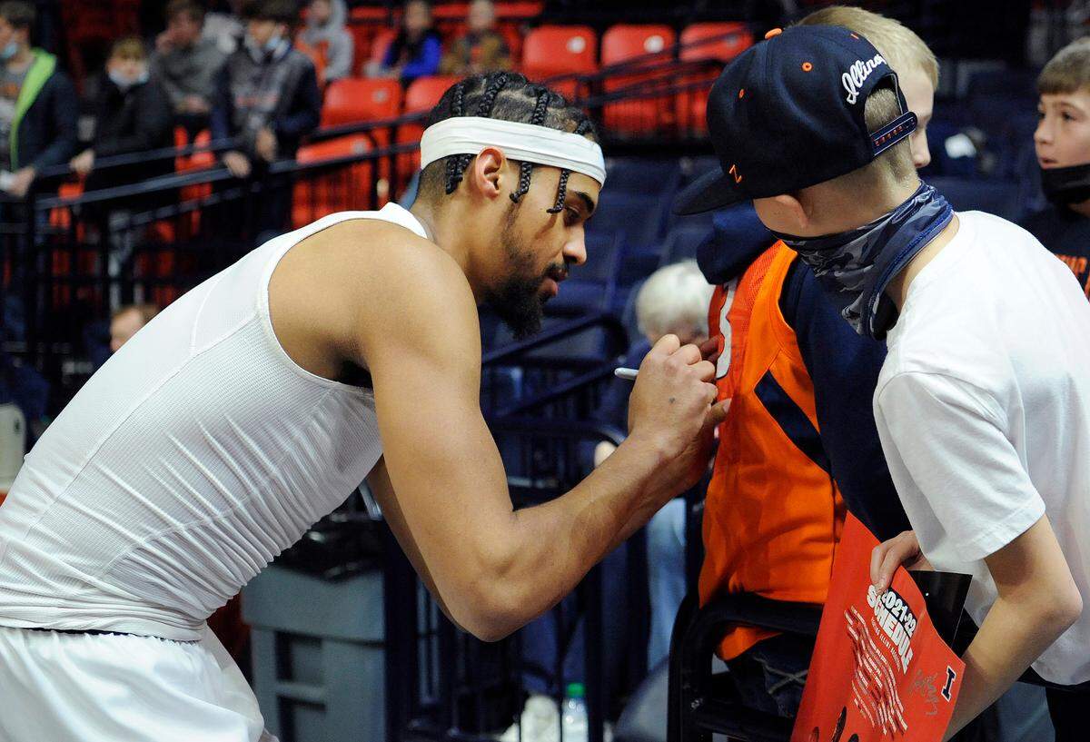 Illinois’ Jacob Grandison signs the back of a fan’s shirt before the start of their game against Purdue Monday, Jan. 17, 2022, in Champaign, Ill.