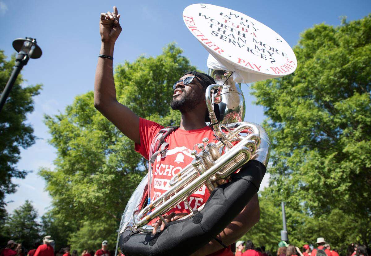 Donald Parker III, a music teacher at Northside Elementary School in Chapel Hill, NC, waves to someone in the growing crowd outside of the NCAE building on Wednesday morning, May 1, 2019. Thousands gathered in downtown Raleigh for the second teacher’s march and rally.