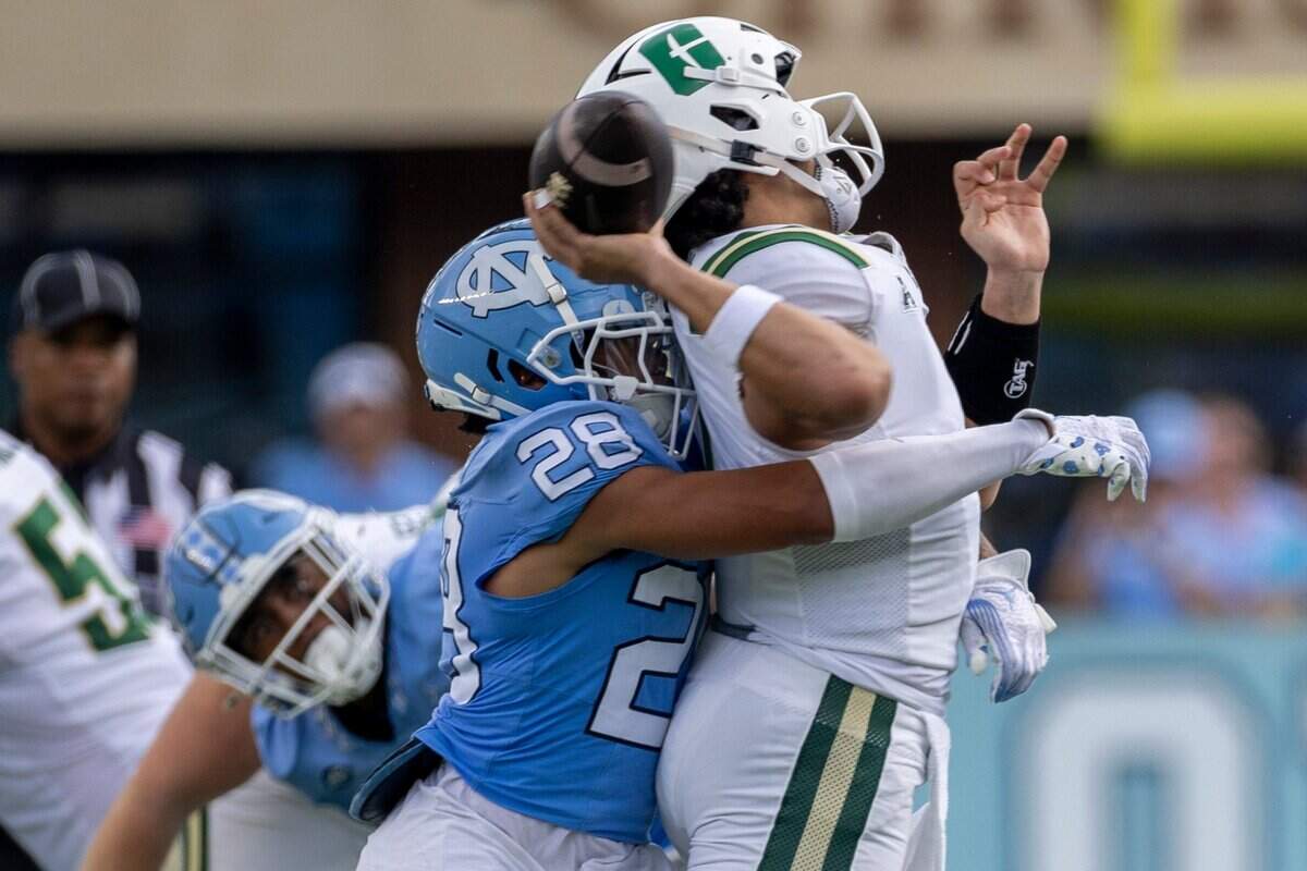 Charlotte quarterback Max Brown (1) is hit by North Carolina defensive back Alijah Huzzie (28) in the first quarter on Saturday, September 7, 2024 at Kenan Stadium in Chapel Hill, N.C.