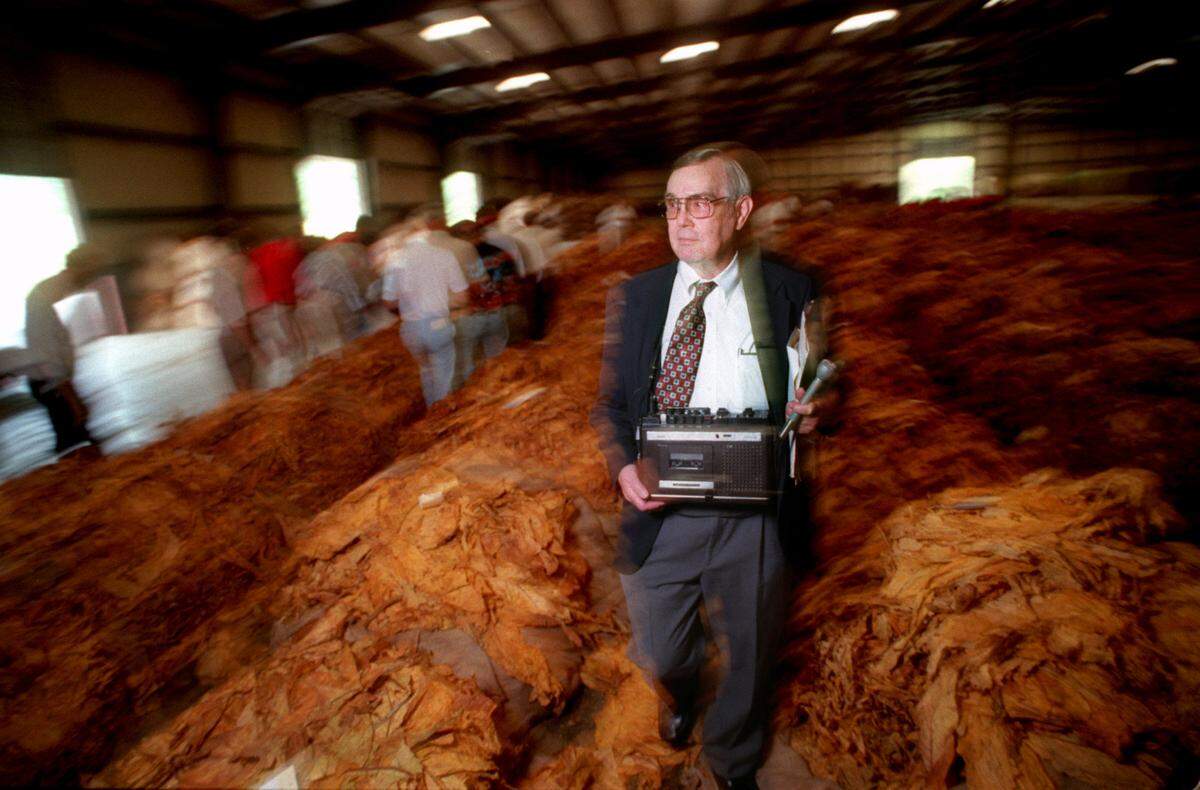 Carl Lamm heads back down a row of tobacco after getting a soundbite from the auctioneer at Carolina Farmer’s Cooperative Tobacco Warehouse in Smithfield in 1997. Each morning during the market, Lamm would head out to tape a segment for his afternoon radio show.