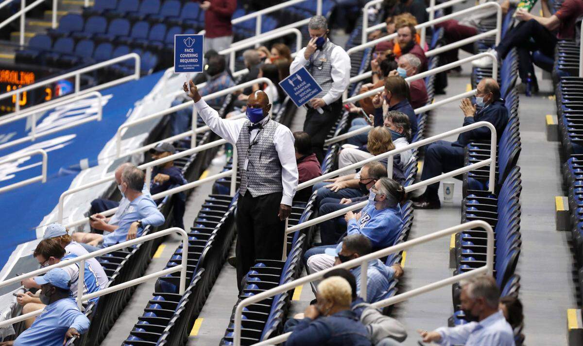 Ushers remind fans to maintain social disancing and to wear a mask during a timeout in the second half of UNC’s 81-73 victory over Virginia Tech in the quarterfinals of the ACC Men’s Basketball Tournament in Greensboro, N.C., Thursday, March 11, 2021.
