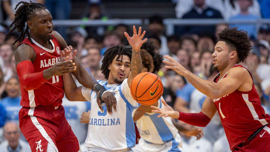 North Carolina guard Elliot Cadeau (3) tries for a steal from Alabama center Clifford Omoruyi (11) and guard Mark Sears (1) in the first half on Wednesday, December 4, 2024 at the Smith Center in Chapel Hill, N.C.