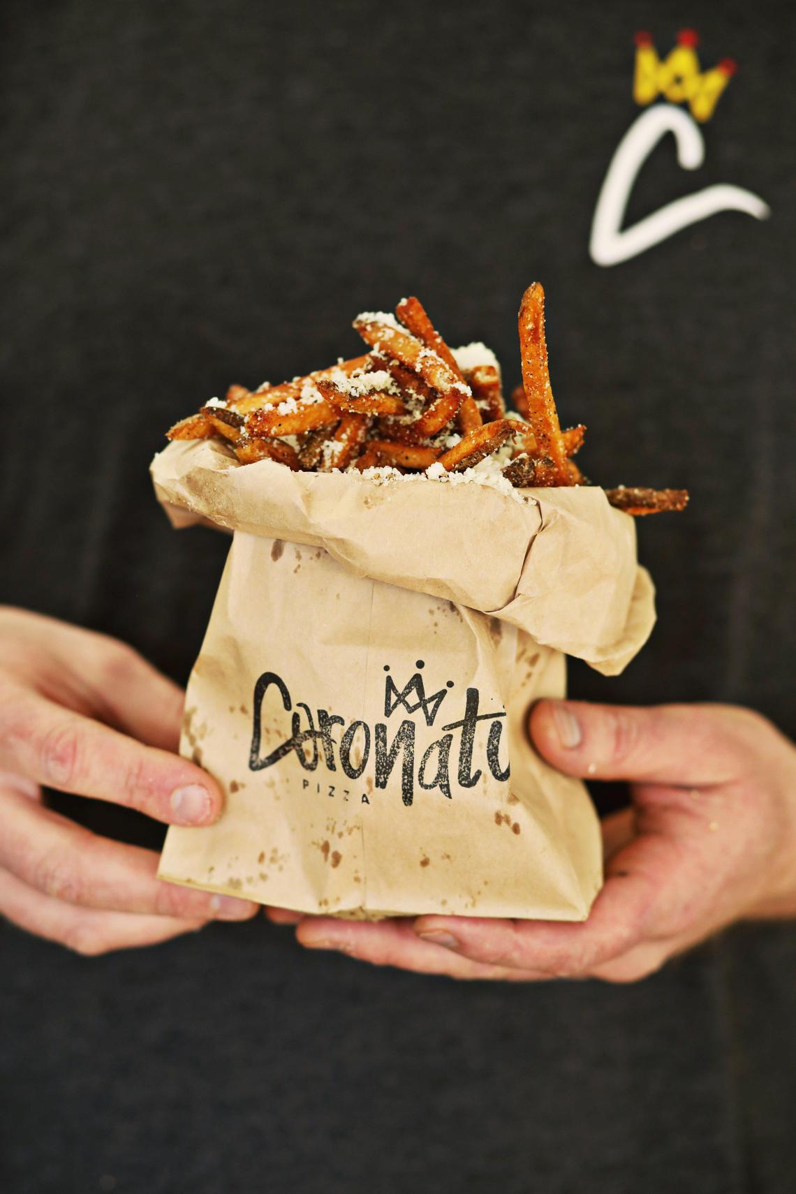 The cacio e pepe fries at Coronato are liberally dusted with black pepper and pecorino Romano and charmingly served in a paper bag.