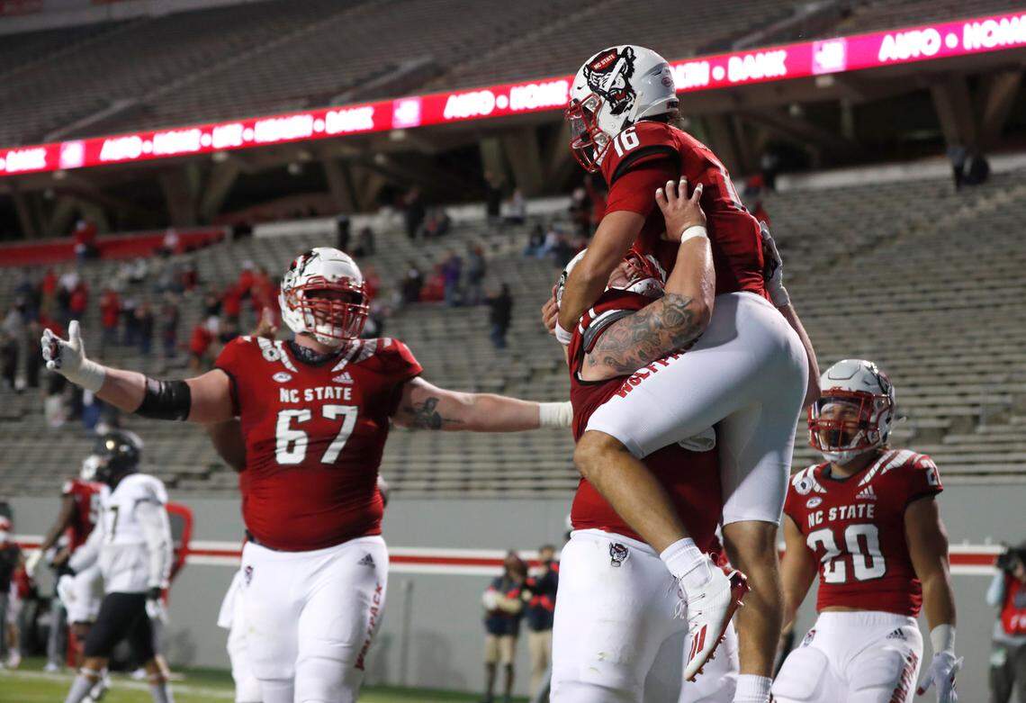 N.C. State guard Joe Sculthorpe (71) lifts up quarterback Bailey Hockman (16) after Hockman scored on a 7-yard touchdown run during the first half of N.C. State’s game against Wake Forest at Carter-Finley Stadium in Raleigh, N.C, Saturday, Sept. 19, 2020. N.C. State offensive tackle Justin Witt (67) is to the left.