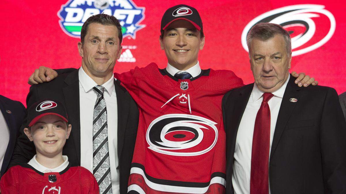 Ryan Suzuki smiles while wearing a Carolina Hurricanes jersey during the first round of the NHL hockey draft Friday, June 21, 2019, in Vancouver, British Columbia. Because of the pandemic the draft was held remotely in 2020 and 2021.