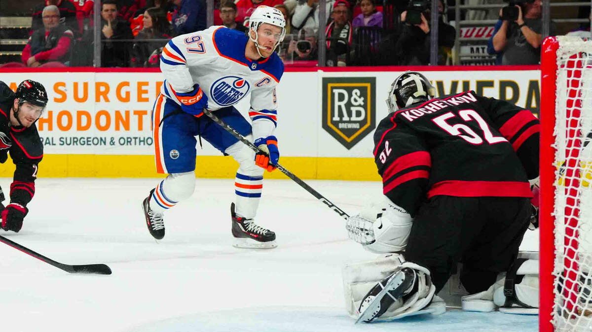 Nov 22, 2023; Raleigh, North Carolina, USA; Edmonton Oilers center Connor McDavid (97) takes at the puck in on Carolina Hurricanes goaltender Pyotr Kochetkov (52) during the second period at PNC Arena. Mandatory Credit: James Guillory-USA TODAY Sports