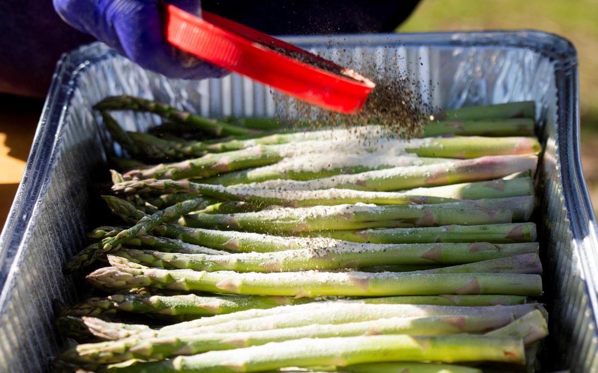 Fresh asparagus receives a dusting of spices on the final day of a the five-day no-contact cookout known as Feed Durham that began as a response to the increase of food insecurity at the start of coronavirus pandemic, bringing dozens of volunteers together every six to eight weeks to cook well-seasoned and nutrient-dense meals for people in need, on Wednesday, Mar. 3, 2021, in Durham, N.C.