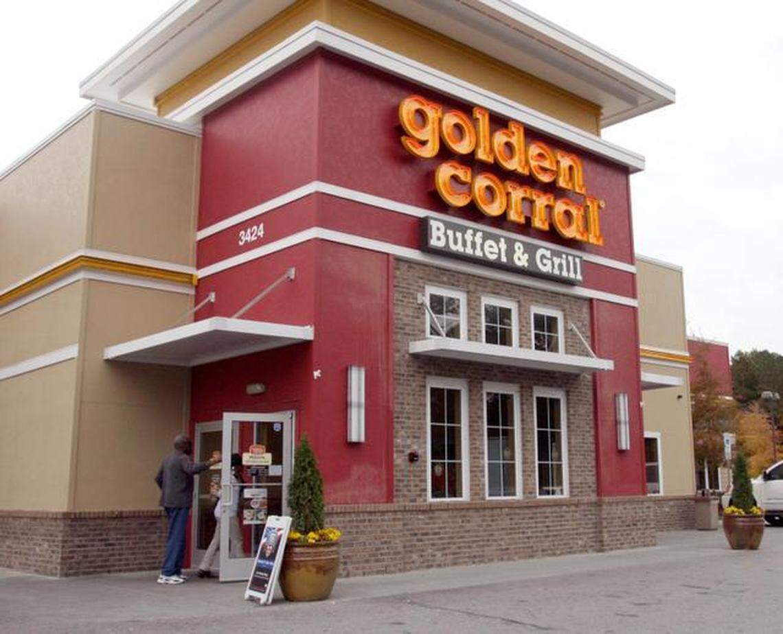 The exterior of a Golden Corral Buffet & Grill restaurant building on a cloudy day. The building has red and tan sections, a prominent Golden Corral sign, and a brick base. A person is seen entering the front doors.