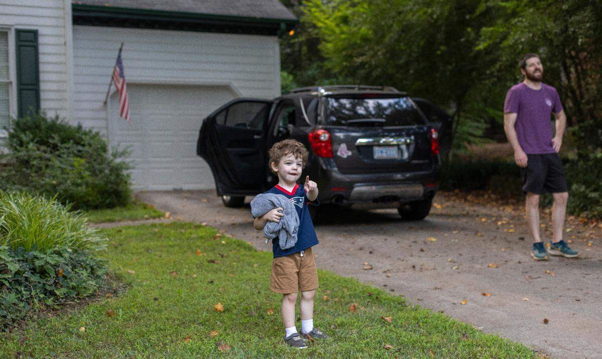 Three-year-old Camden Harrington waves to Raleigh Solid Waste Services employee Alonzo Adams as he makes his rounds Wednesday, July 17, 2024 in Raleigh, N.C.