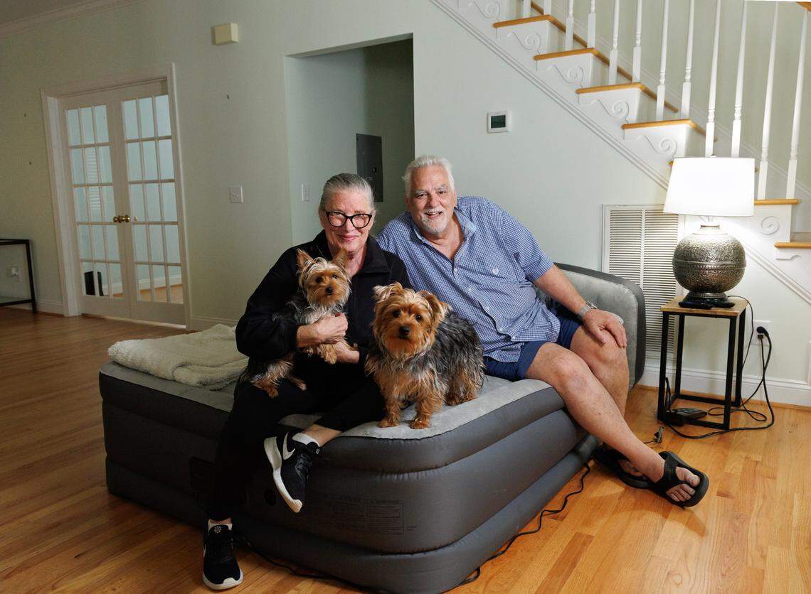 Annabella and Larry Vagonis sit with their nine-month-old Yorkshire Terriers, Ruby and Dexter, on an inflatable mattress at their new home in Chapel Hill, N.C. on Sunday, May 4, 2025. The couple recently moved to the Triangle from northern Virginia, where they had lived for decades.