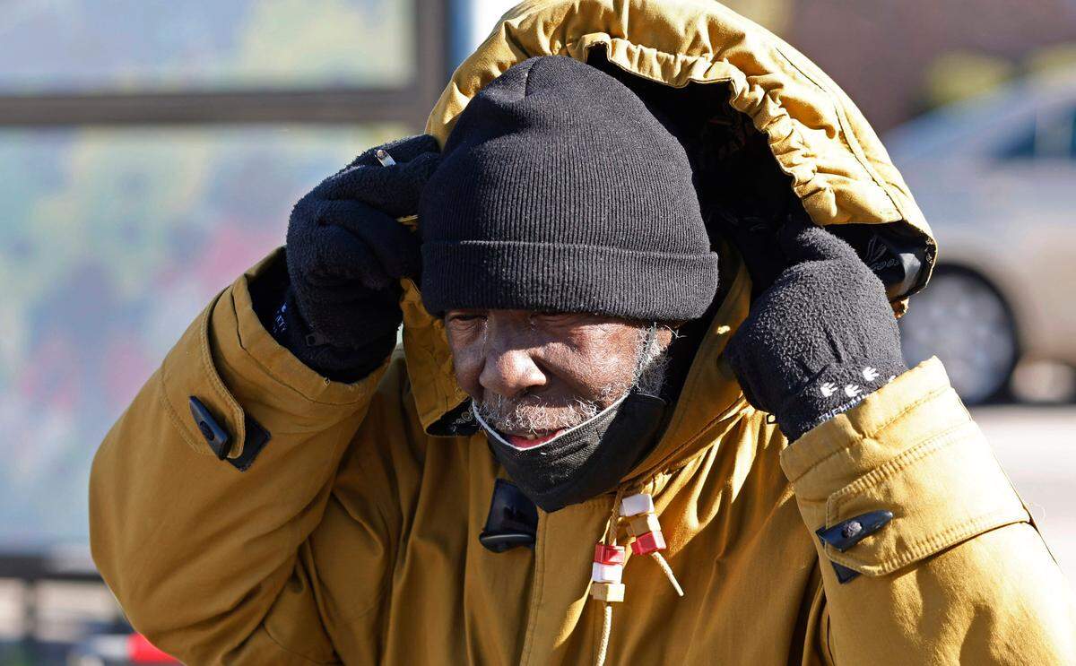 Joe Fleming tries to brace himself from the cold wind as he walks to a store in Southgate Plaza shopping center in Raleigh, N.C., Friday, Dec. 23, 2022. Fleming said he was heading towards the drug store, jokingly saying unless the wind knocked him over.