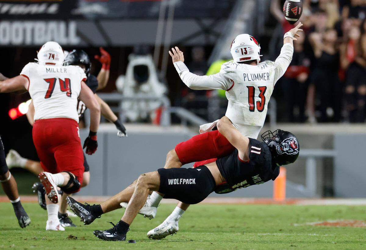 Louisville quarterback Jack Plummer (13) intentionally grounds the ball away as he is tackled by N.C. State linebacker Payton Wilson (11) during the second half of Louisville’s 13-10 victory over N.C. State at Carter-Finley Stadium in Raleigh, N.C., Friday, Sept. 29, 2023.