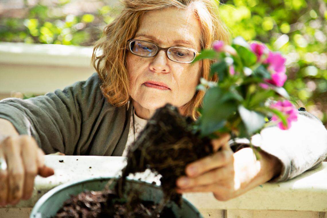 Pam Dickens prepares to plant impatiens in pots along the railing of her porch in Hillsborough on Friday, April 29, 2022. Dickens has been an avid gardener for years.