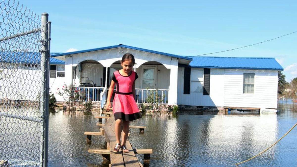 A young girl crosses over a makeshift bridge to exit her family’s mobile home in Robeson County after Hurricane Matthew caused severe flooding in 2016.