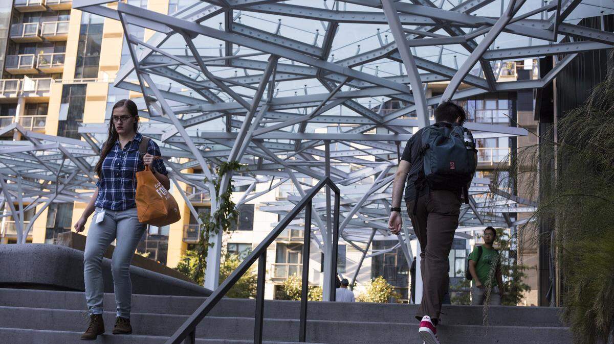 People walk next to the Day 1 building at the Amazon headquarters in Seattle.