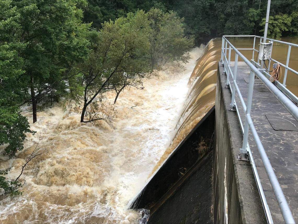 Water flows over the University Lake Dam after heavy rain.