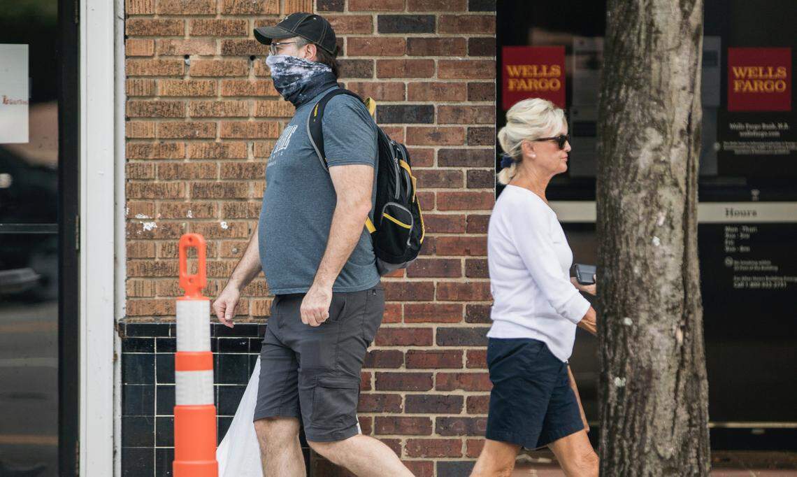Two people pass each other while walking on Franklin Street in Chapel Hill, N.C. on Wednesday, June 10, 2020. Orange County, which will extend its COVID-19-related state of emergency through August, will begin requiring residents to wear face coverings when leaving their homes on Friday, according to a county press release.