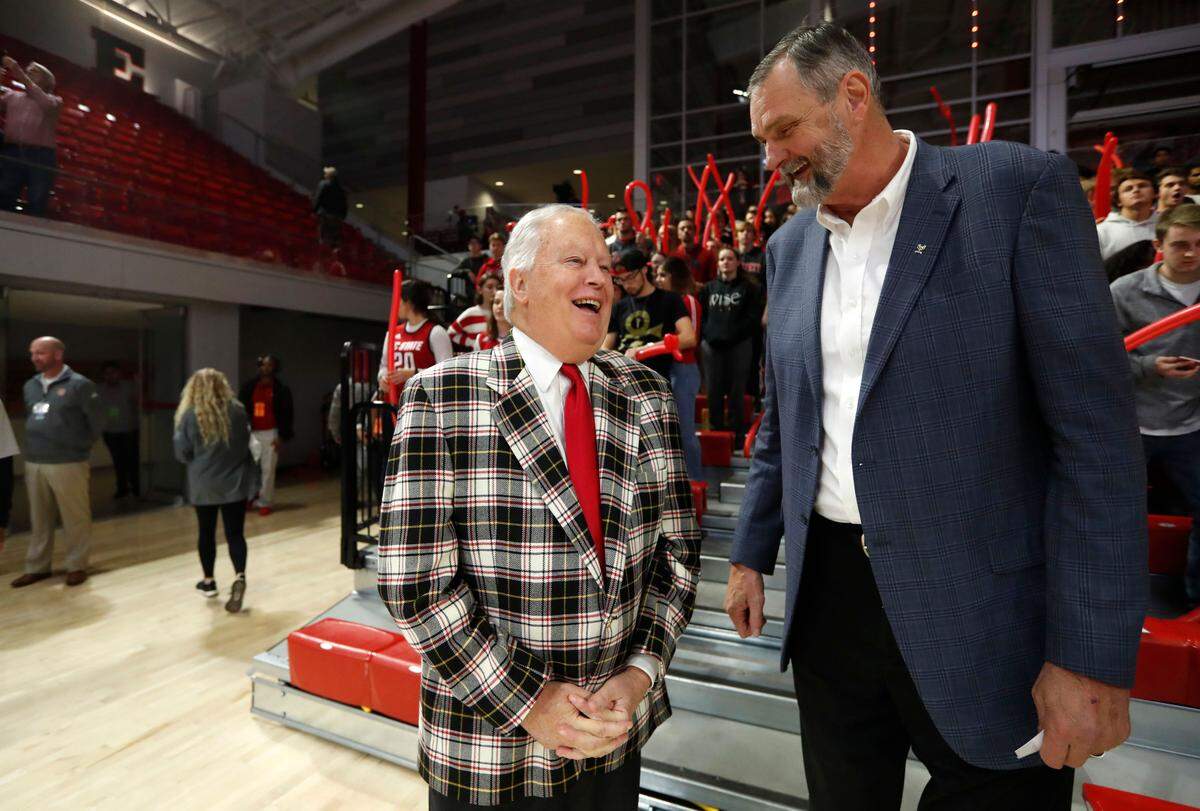 Bobby Purcell, the executive director of N.C. State’s Wolfpack Club, left, laughs with Tommy Burleson before the Wolfpack’s Heritage game against Alcorn State at Reynolds Coliseum in Raleigh, N.C., Tuesday, Nov. 19, 2019. Purcell is wearing former coach Norm Sloan’s jacket as a way to honor Coach Sloan in Reynolds.
