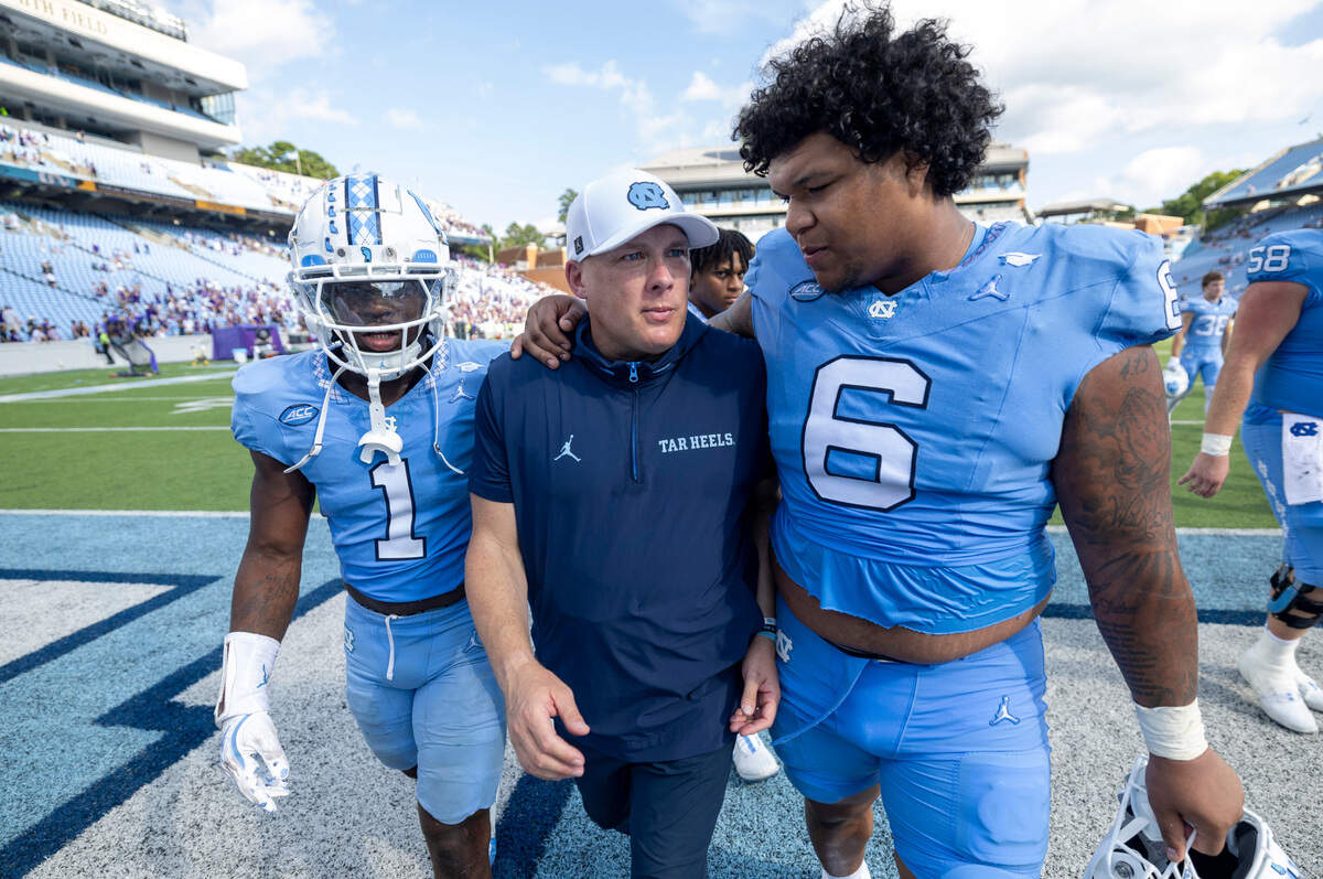 North Carolina defensive coordinator Geoff Collins is embraced by defensive lineman Joshua Harris (6) as they leave the field following the Tar Heels’ 70-50 loss to James Madison on Saturday, September 21, 2024 at Kenan Stadium in Chapel Hill, N.C.