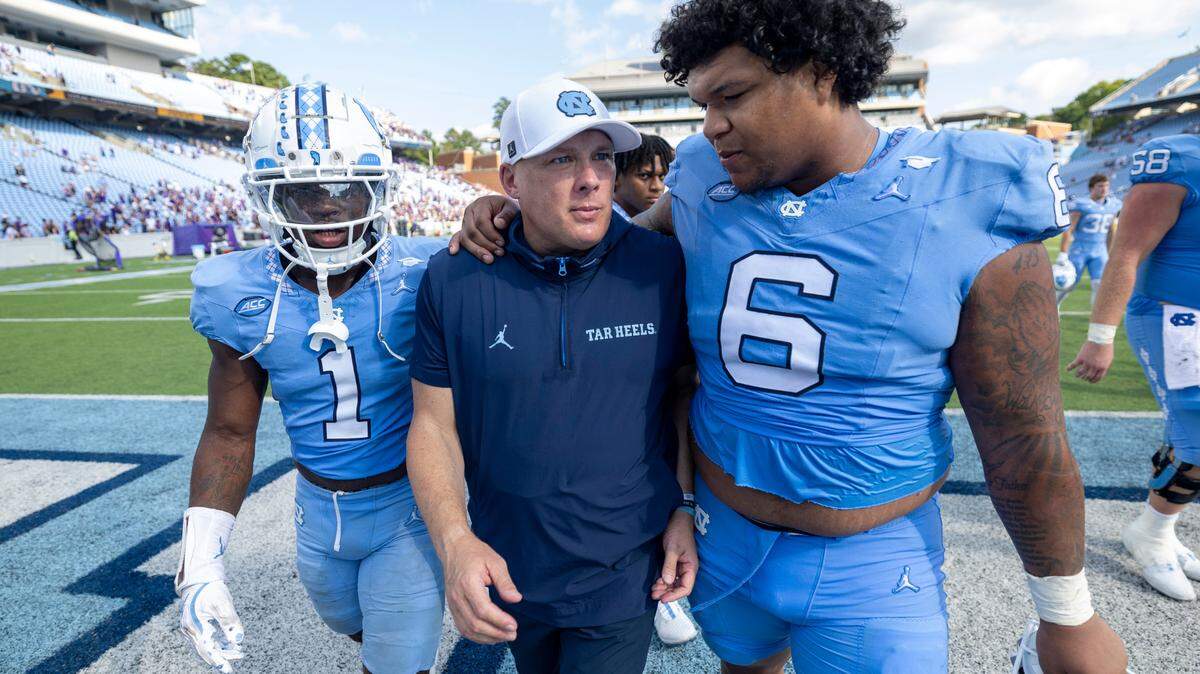 North Carolina defensive coordinator Geoff Collins is embraced by defensive lineman Joshua Harris (6) as they leave the field following the Tar Heels’ 70-50 loss to James Madison on Saturday, September 21, 2024 at Kenan Stadium in Chapel Hill, N.C.