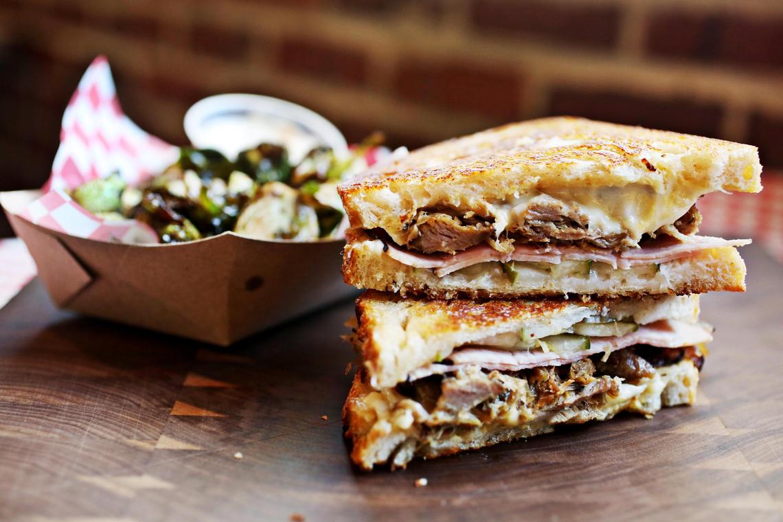 The Cubano sandwich (smoked pork, house-made pickles, Swiss cheese, ham, roasted red peppers and Dijon) with a side of flash-fried Brussels sprouts from American Meltdown, which occupies a spot in the food court at Durham’s Streets at Southpoint mall.