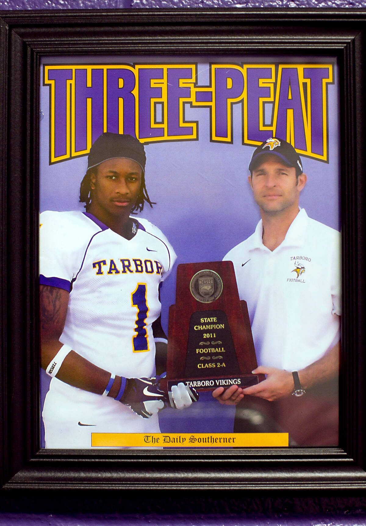 In a framed photograph, Tarboro High School football coach Jeff Craddock poses with star player Todd Gurley and the 2011 state championship trophy. Gurley who is now playing at Georgia is a potential Heisman Trophy candidate.