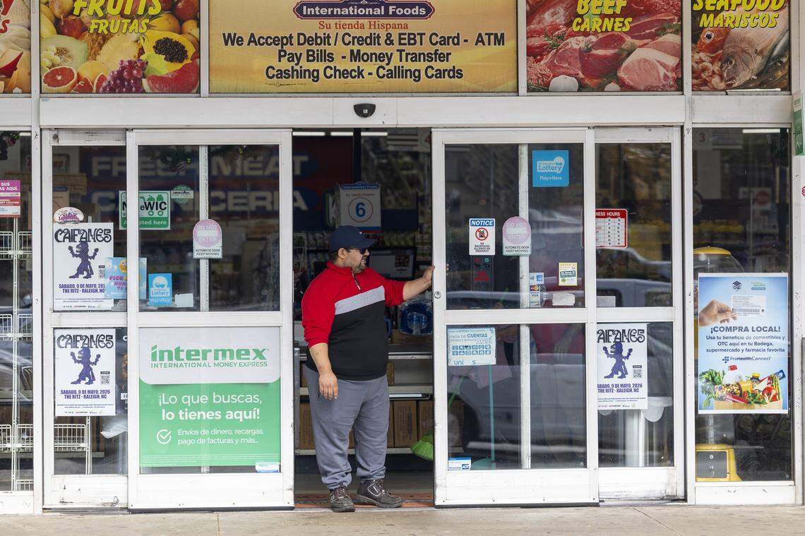 A security guard operates an automatic sliding door while watching the parking lot outside the International Foods grocery on New Hope Church Road in Raleigh on Wednesday, Nov. 19, 2025, after federal immigration enforcement agents were seen circulating the area in unmarked SUVs. Immigrant rights groups said federal agents detained at least 12 Triangle residents on Tuesday, including in Raleigh, Durham and Cary.