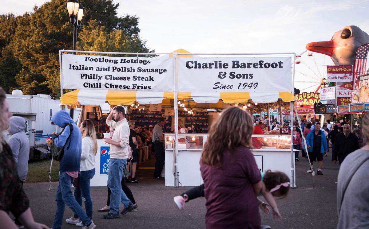 Fairgoers walk past the Charlie Barefoot and Sons tent on Wednesday, Oct 17, 2018, which was opened by Charlie Barefoot in 1949.