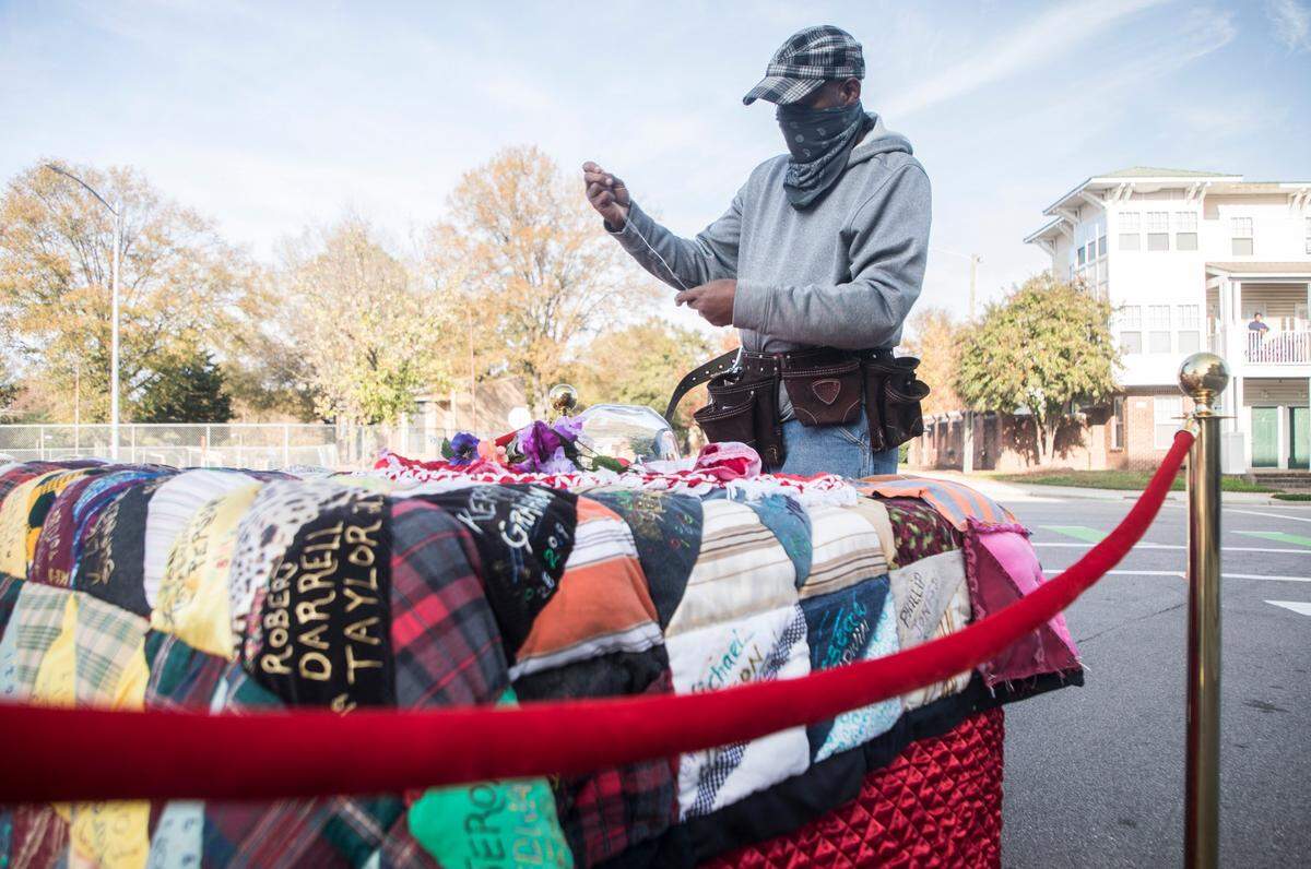 Sidney Brodie, who created the Durham Homicide and Victims of Violent Death Memorial Quilt, sews more names onto the quilt during a “Guns Down Hearts Up” march against gun violence at the Durham Police Department Headquarters in Durham, N.C. on Saturday, Nov. 14, 2020.