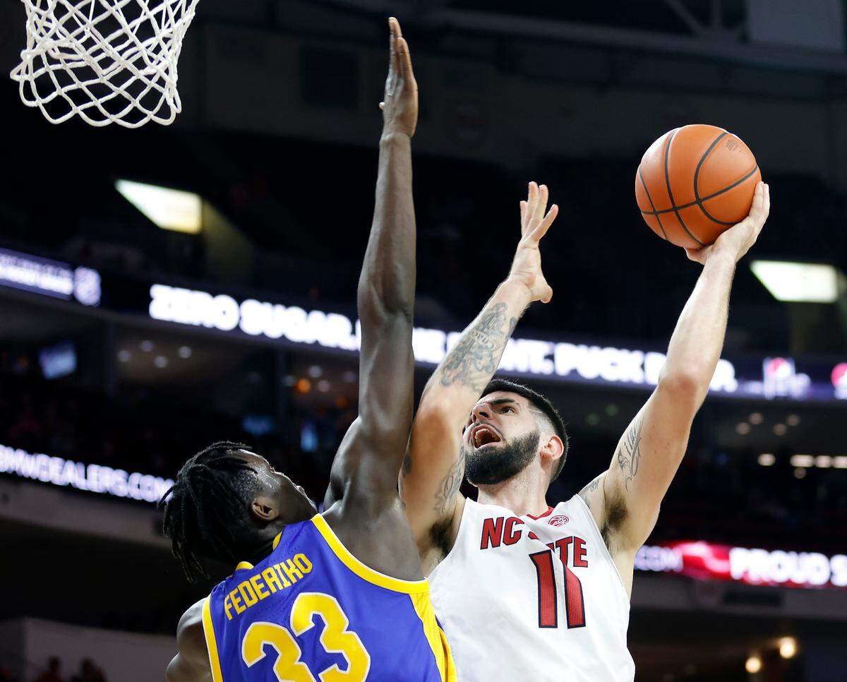N.C. State’s Dusan Mahorcic is fouled as he drives against Pitt’s Federiko Federiko during the second half of a men’s basketball game at PNC Arena on Friday, Dec. 2, 2022, in Raleigh, N.C.