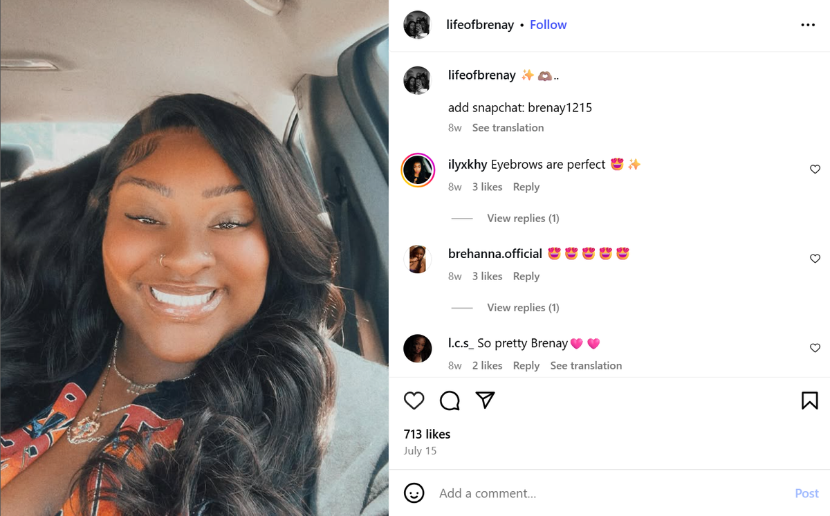 Brenay Kennard takes a selfie while smiling in her car. She has long, straight black hair with a side part, a nose ring and is wearing two necklaces.