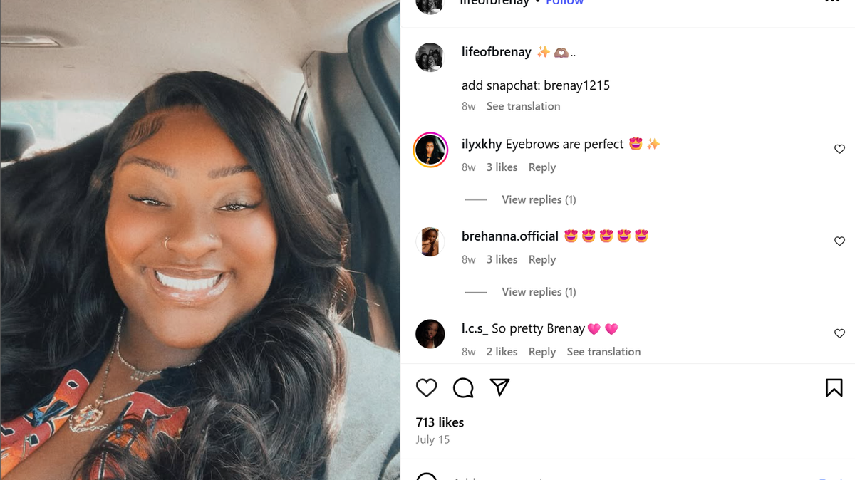 Brenay Kennard takes a selfie while smiling in her car. She has long, straight black hair with a side part, a nose ring and is wearing two necklaces.