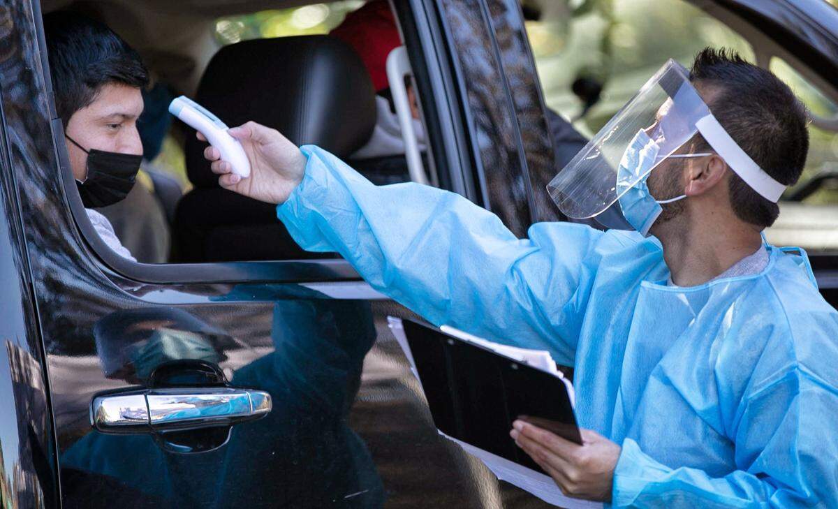 Participants at a COVID-19 testing site manned by Advance Community Health have their temperatures taken prior to being administered a nasal swap test during on Village Court in Garner, N.C. on Wednesday, November 18, 2020.