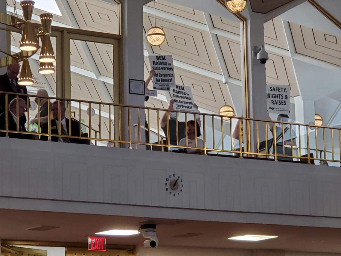 Workers’ rights protesters held signs and chanted outside the North Carolina House gallery on Thursday during the state budget debate. About a dozen protesters left after briefly stopping the floor debate.