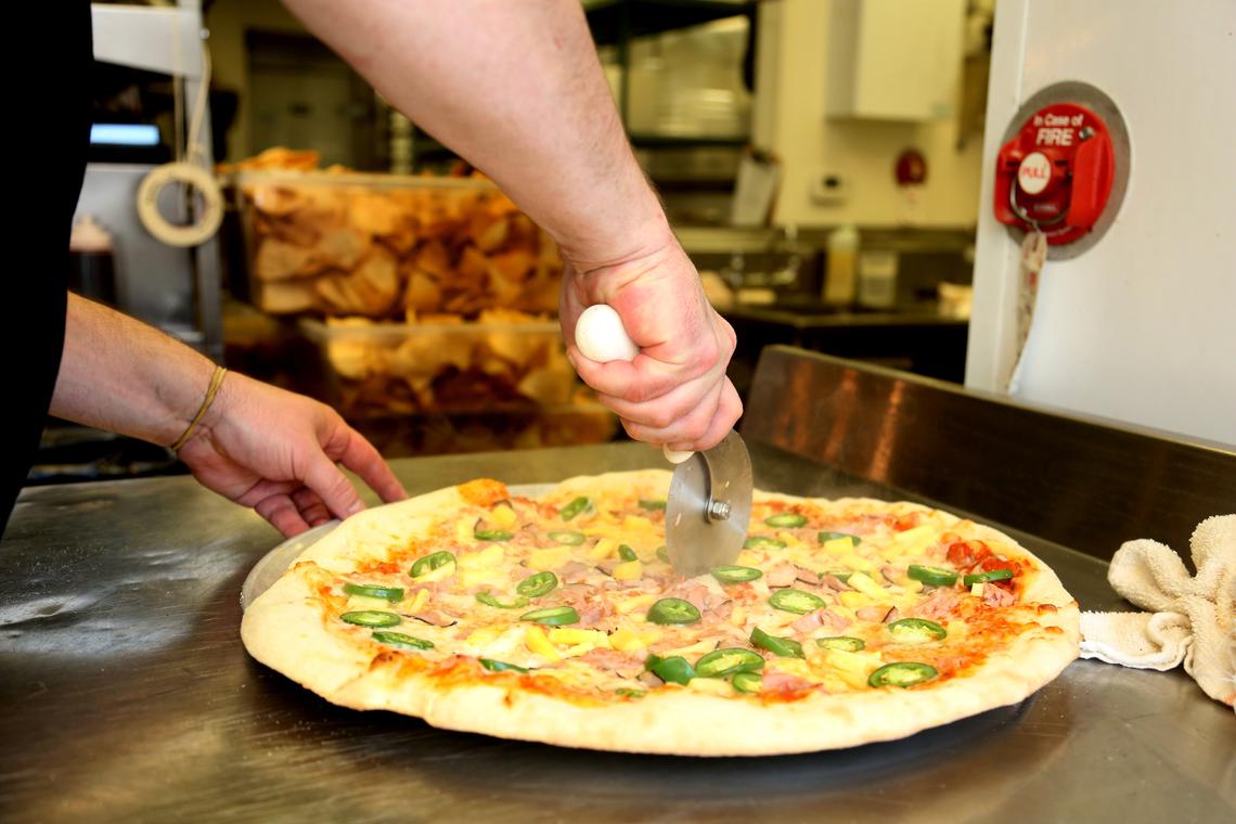 Chef Michael Rehm slices the Fiery Hawaii, a specialty pizza fresh out of the oven, at Pizza Times in downtown Raleigh Friday, April 13, 2018.