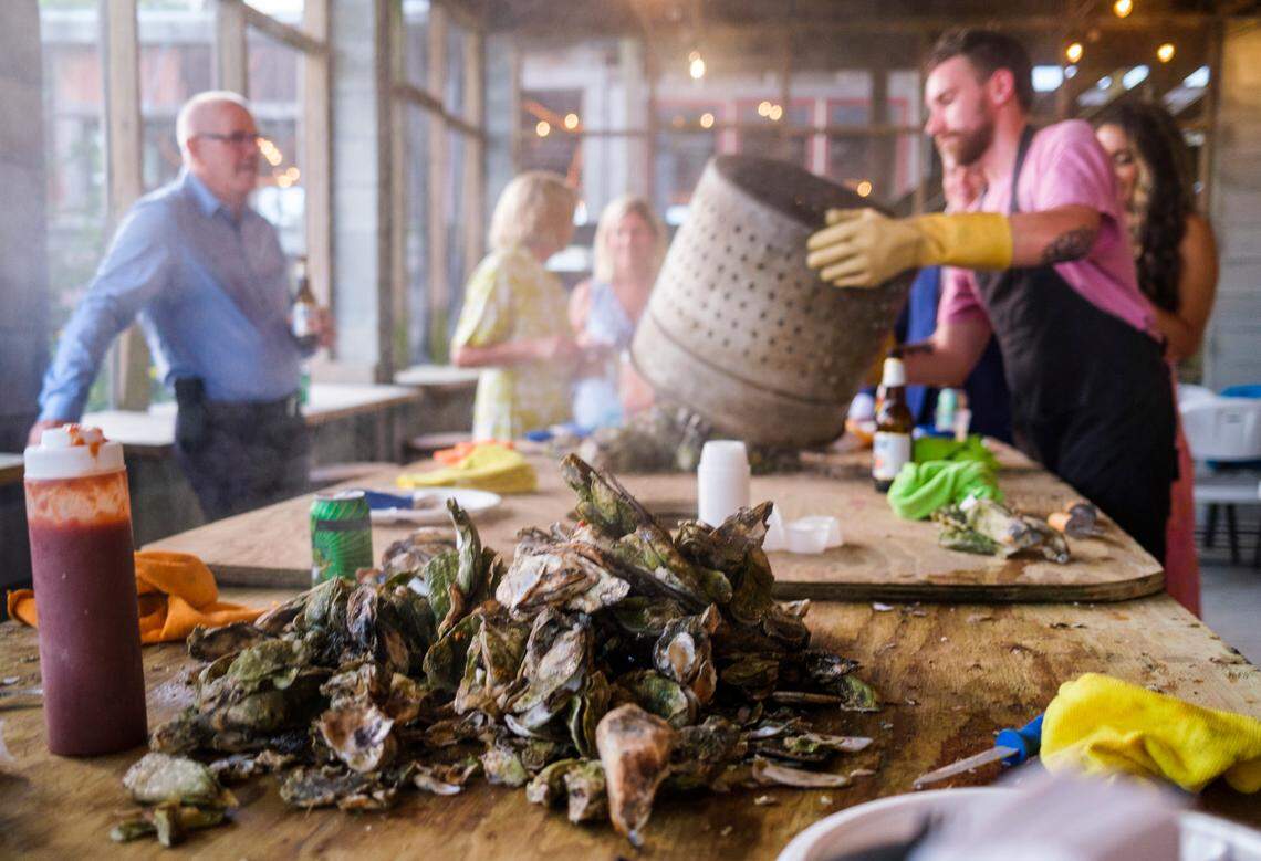 Tyler Howerton pours steaming oysters onto a table at Bowen’s Island Restaurant during an oyster roast event for a wedding rehearsal party with some of the season’s first oysters from the Folly River near Charleston, S.C. Oct. 8, 2021.