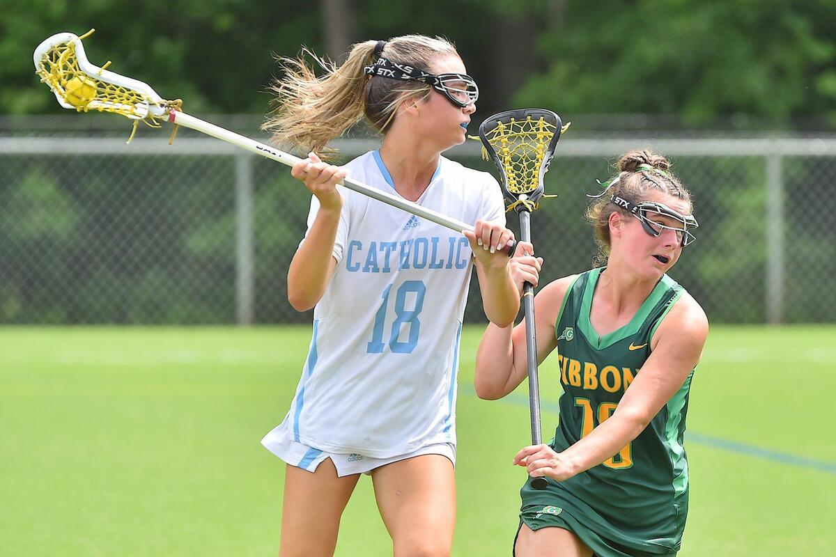 Charlotte Catholic’s Molly Baumgratz (18) looks to pass against Cardinal Gibbons’ Charlotte Jackson (10) in the first half. The Cardinal Gibbons Crusaders and the Charlotte Catholic Cougars met in the NCHSAA Women’s Lacrosse Championships in Cary, N.C. on May 21, 2022.