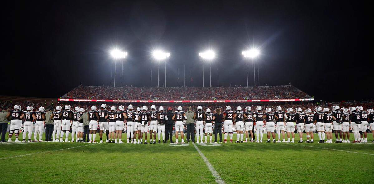 The Wolfpack football team locks arms during an ACC unity moment before N.C. State’s game against Virginia Tech at Carter-Finley Stadium in Raleigh, N.C., Thursday, Oct. 27, 2022.