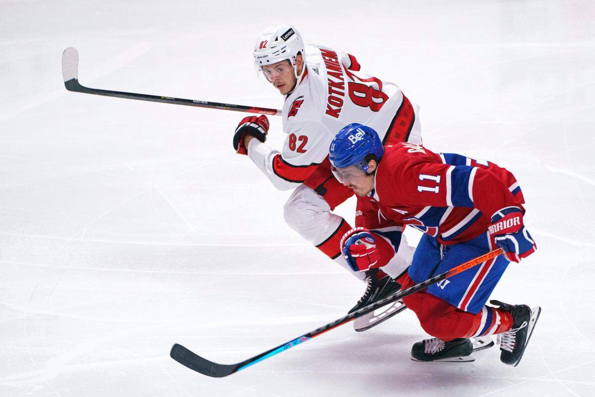 Carolina Hurricanes’ Jesperi Kotkaniemi, top, and Montreal Canadiens’ Brendan Gallagher skate toward the puck during the first period of an NHL hockey game Thursday, Oct. 21, 2021, in Montreal. (Paul Chiasson/The Canadian Press via AP)