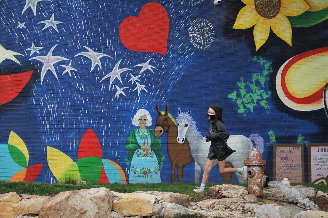 A girl runs past part of the new 150-foot mural at the Lakewood Shopping Center in Durham on Saturday, Nov. 7, 2020. The project was led by artists Cornelio Campos and Estephani Sanchez in collaboration with El Futuro, a mental health clinic, and The Scrap Exchange, a creative reuse center, on Chapel Hill Road.