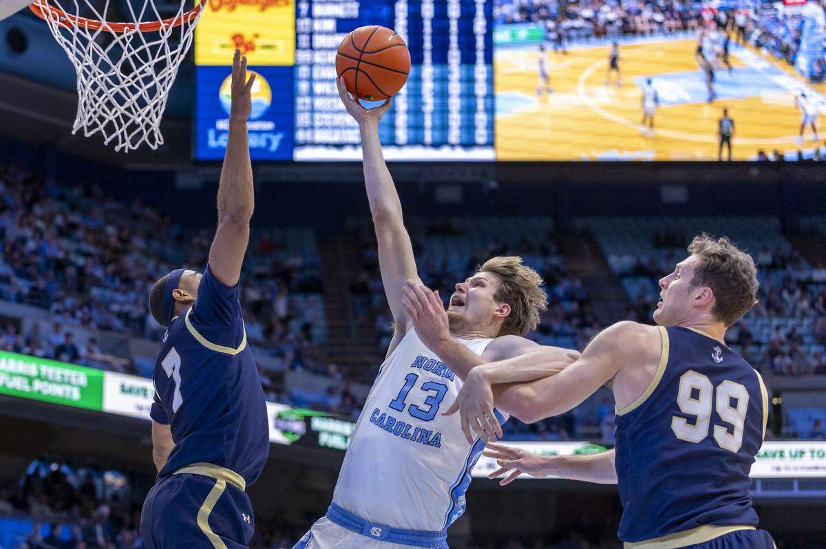 North Carolina center Henri Veesaar (13) drives to the basket against Navy guard David Burnett (7) and center Aidan Kehoe (99) in the first half on Tuesday, November 18, 2025 at the Smith Center in Chapel Hill, N.C.