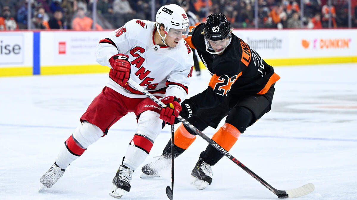 Carolina Hurricanes’ Teuvo Teravainen, left, plays the puck past the defense of Philadelphia Flyers’ Oskar Lindblom during the first period of an NHL hockey game, Monday, Feb. 21, 2022, in Philadelphia. (AP Photo/Derik Hamilton)