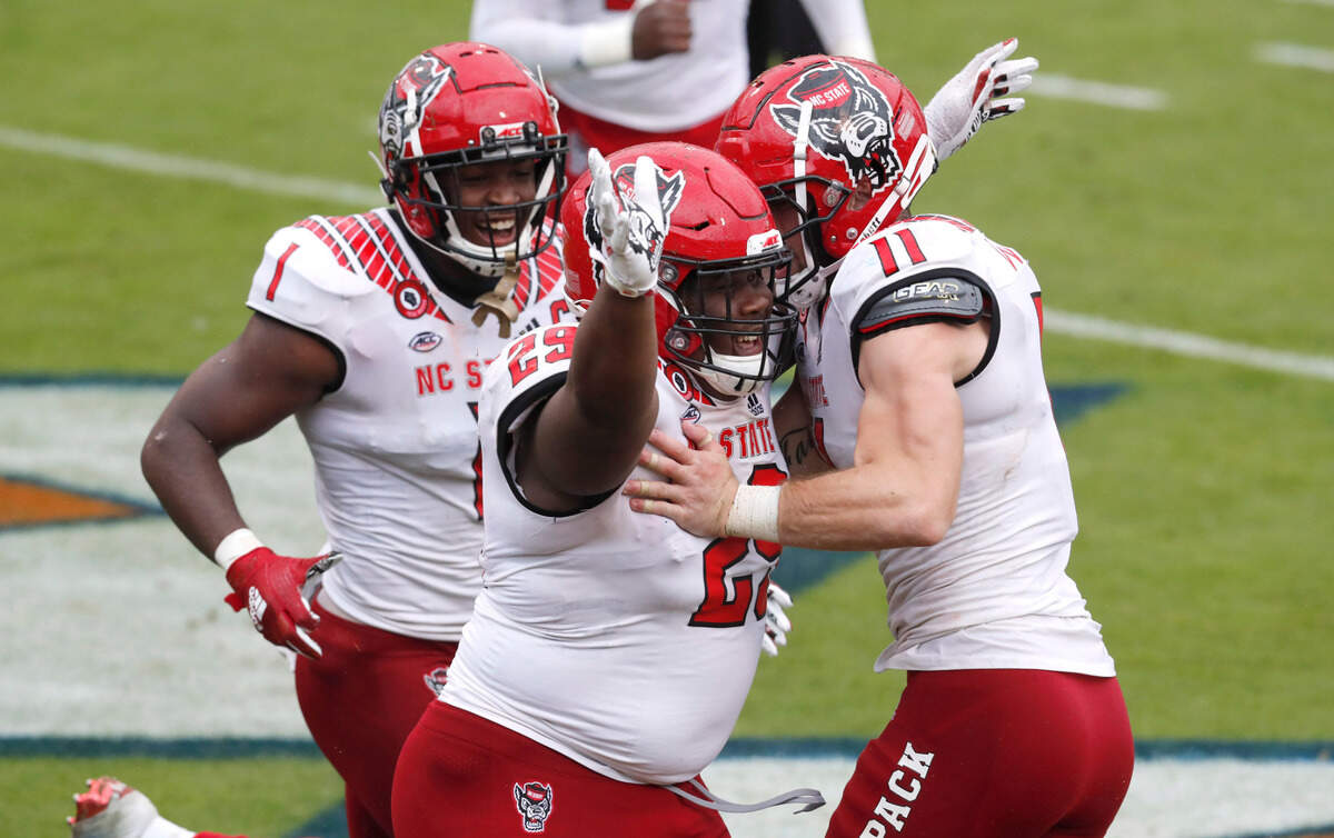 N.C. State defensive tackle Alim McNeill (29) celebrates with Isaiah Moore (1), left, and Payton Wilson (11) after returning an interception for a touchdown during the second half of N.C. State’s 38-21 victory over Virginia at Scott Stadium in Charlottesville, Va., Saturday, Oct. 10, 2020.