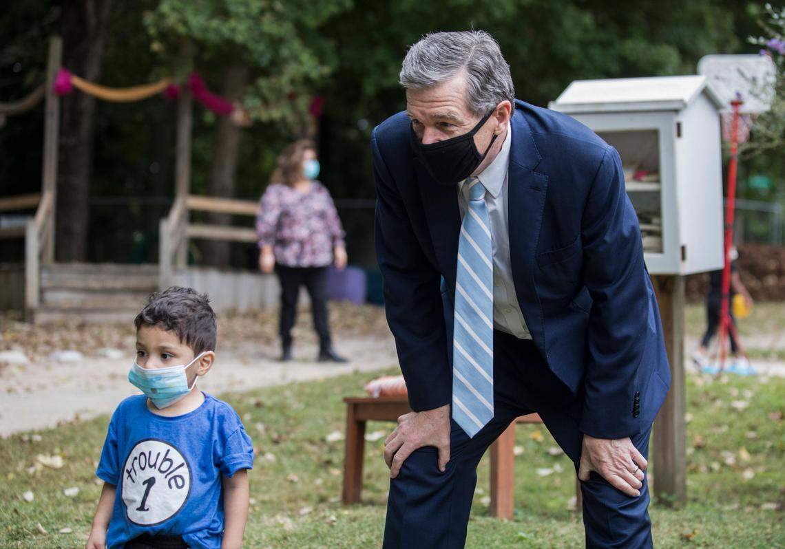 Gov. Roy Cooper visits with children on the playground at the Community School for People Under Six in Carrboro, N.C., on Thursday, Oct. 7, 2021.