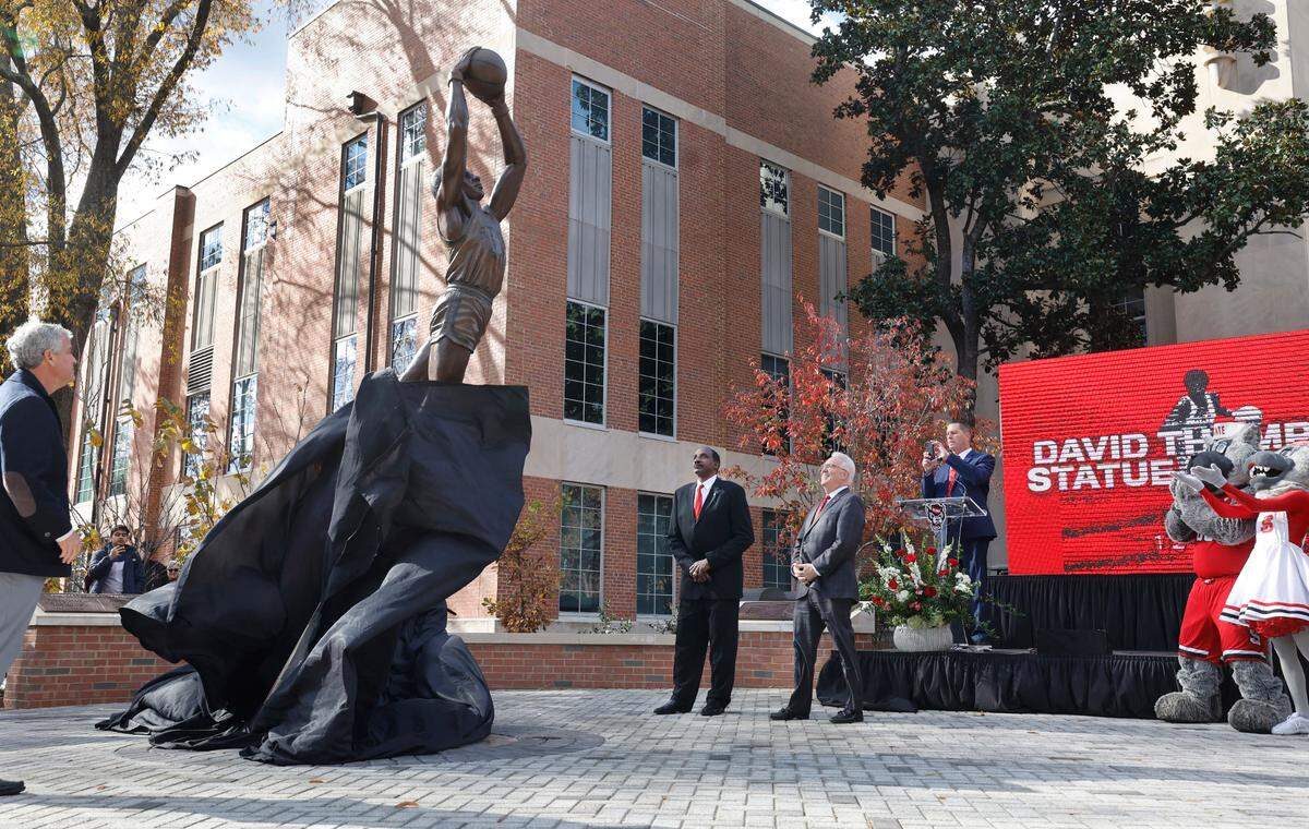 David Thompson watches as his statue is unveiled outside Reynolds Coliseum in Raleigh, N.C., Wednesday, Dec. 6, 2023. Also watching is N.C. State athletics director Boo Corrigan, left, and Chancellor Randy Woodson.